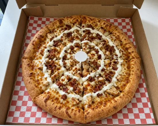 Chicken ranch pizza with grilled chicken, bacon, onions and a ranch sauce swirl in an open pizza box